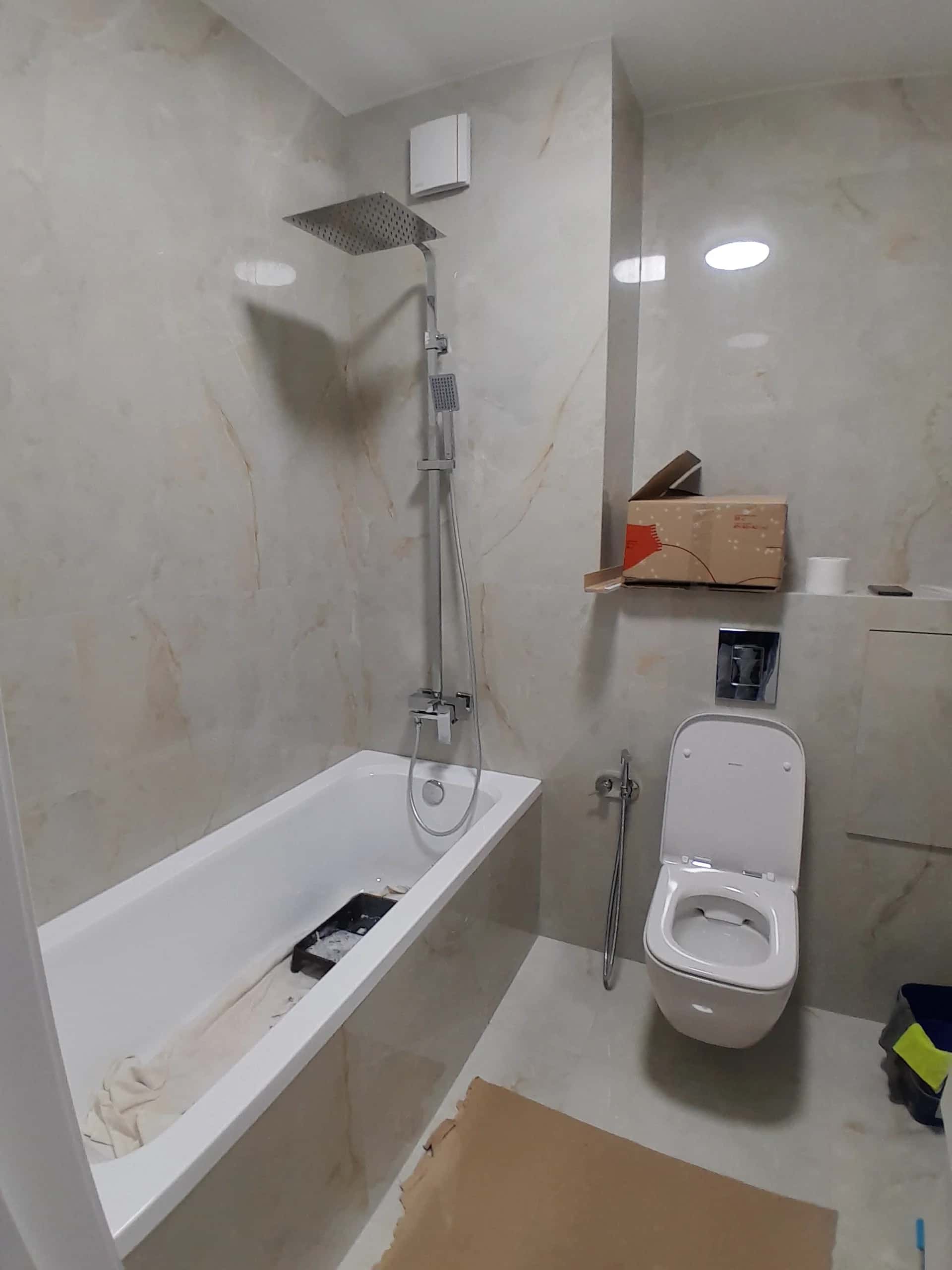 Bathroom with onyx-look porcelain tile and wall-hung toilet during installation