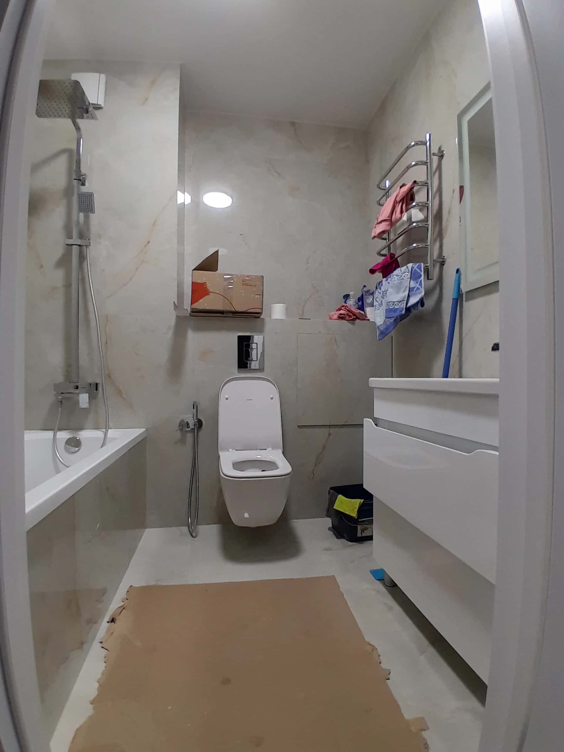 Bathroom with wall-hung toilet and marble-look tiles on walls in beige and cream tones