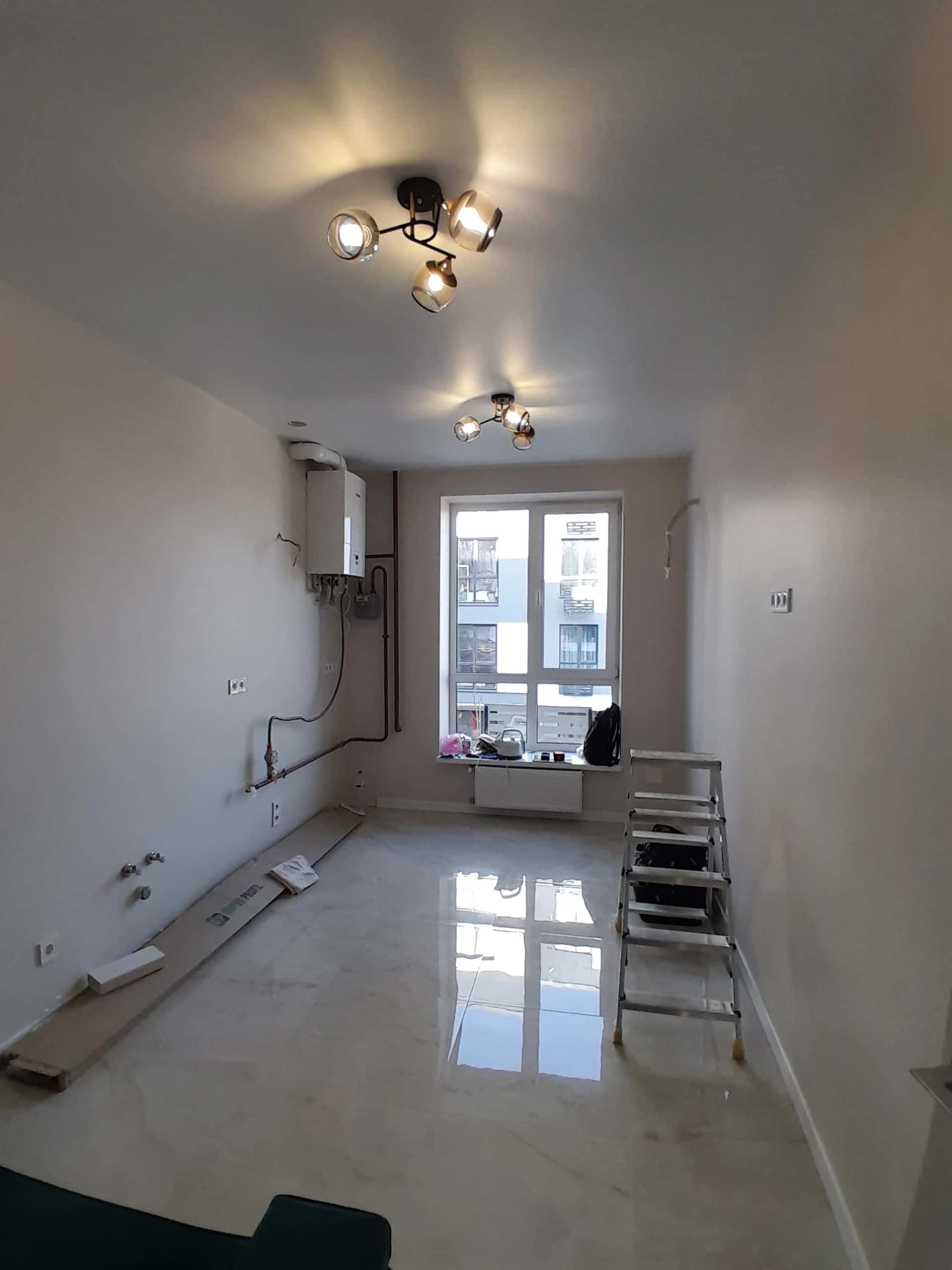 Kitchen during renovation: glossy light marble-look porcelain tile floor and wall-mounted gas boiler