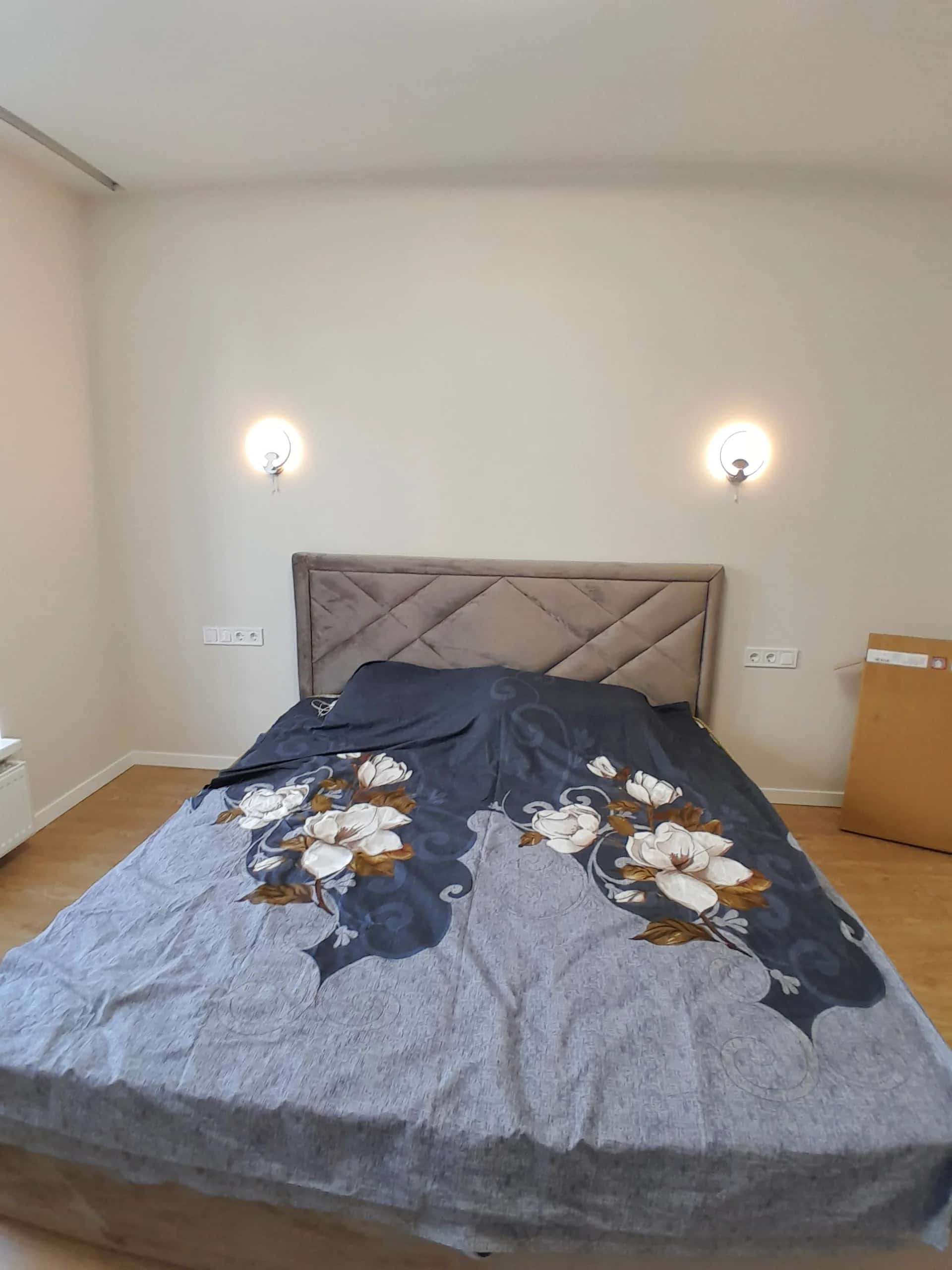 Bedroom with two wall sconces placed symmetrically on either side of the upholstered headboard