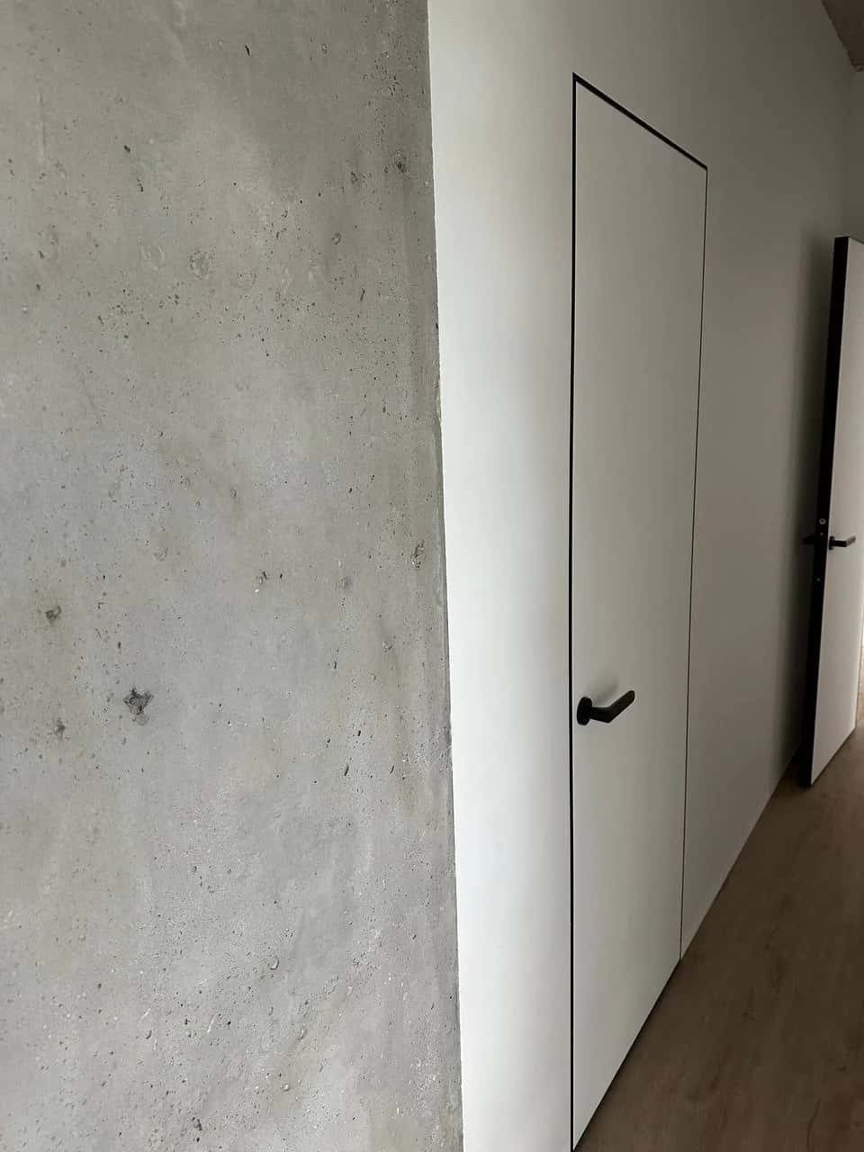 Apartment corridor: decorative concrete-effect plaster and hidden doors with black hardware