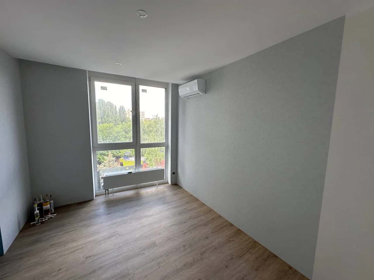 Room with light oak laminate, grey painted walls and floor-to-ceiling panoramic window
