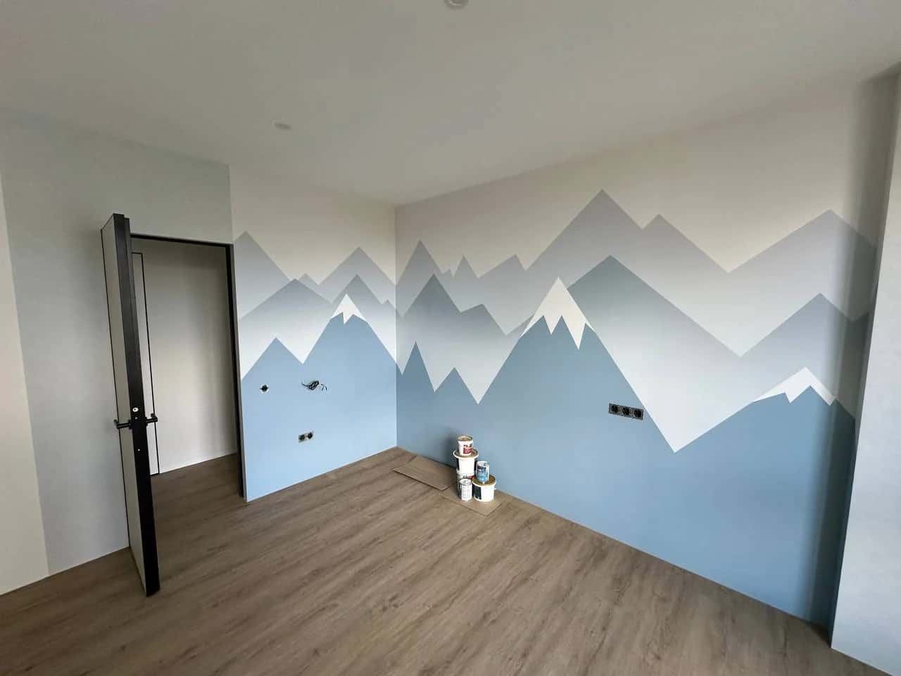 Children's room with a mountain mural painted on the wall in a blue-grey colour palette
