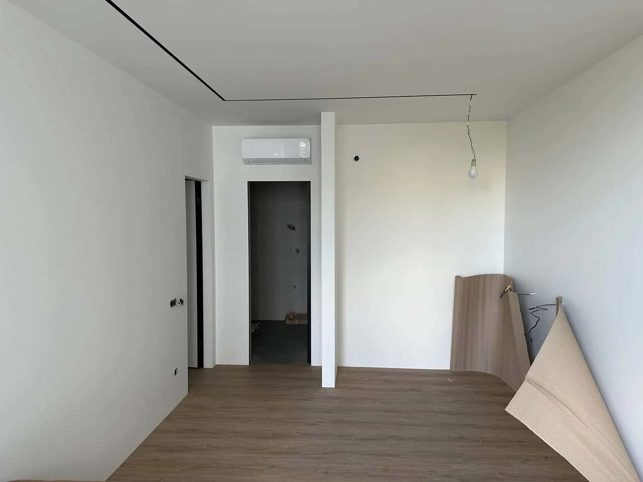 Room at the final stage of renovation: medium-brown laminate flooring and white plastered walls