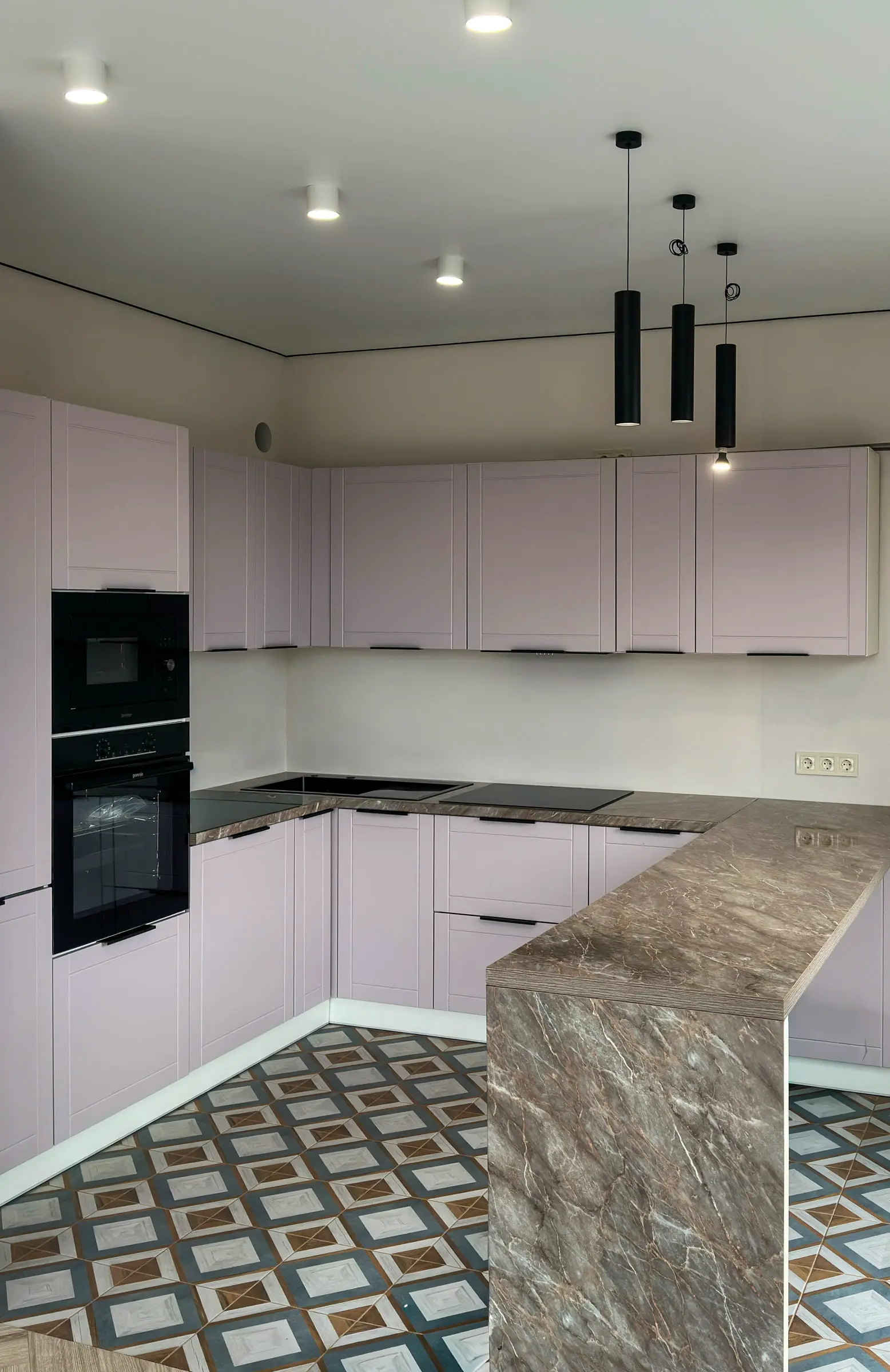 Kitchen with powder-toned facades and an island countertop in brown marble against geometric tile backsplash
