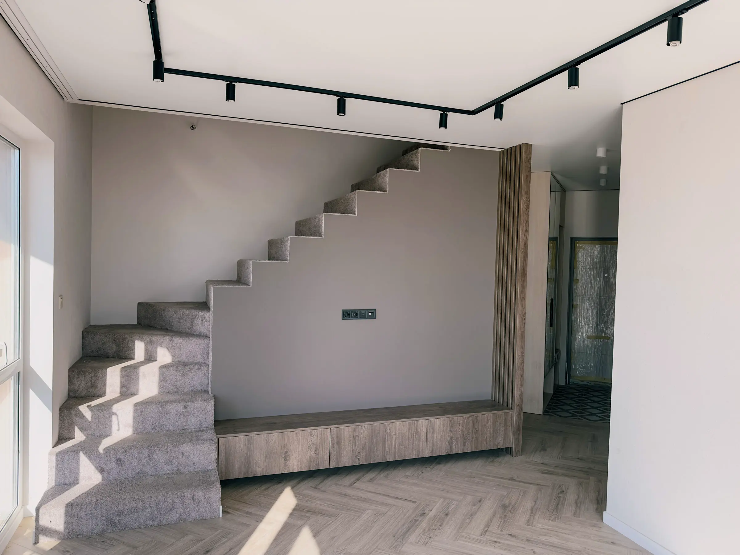 Living room with open-riser concrete stairs and a herringbone parquet floor