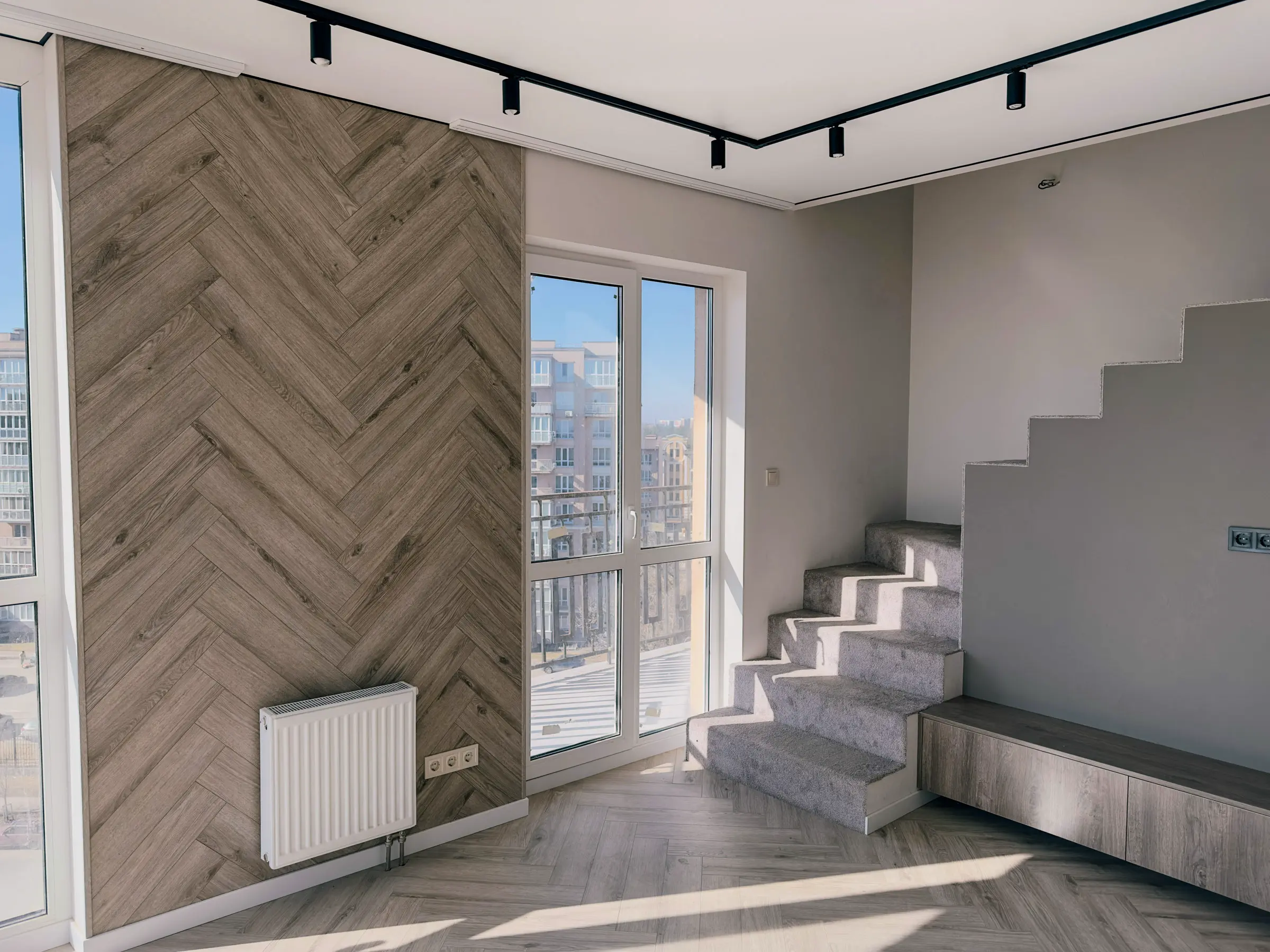 Living room with a wood-effect herringbone accent wall and carpeted stairs