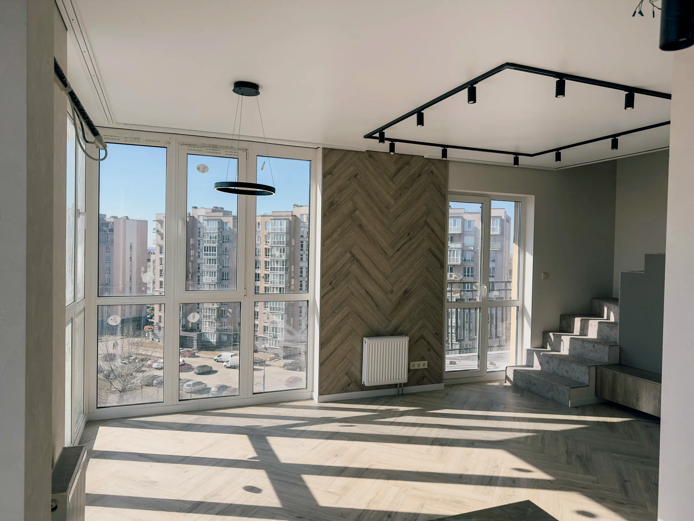 Living room with accent wall clad in wood-look porcelain tiles in a herringbone pattern and track lighting