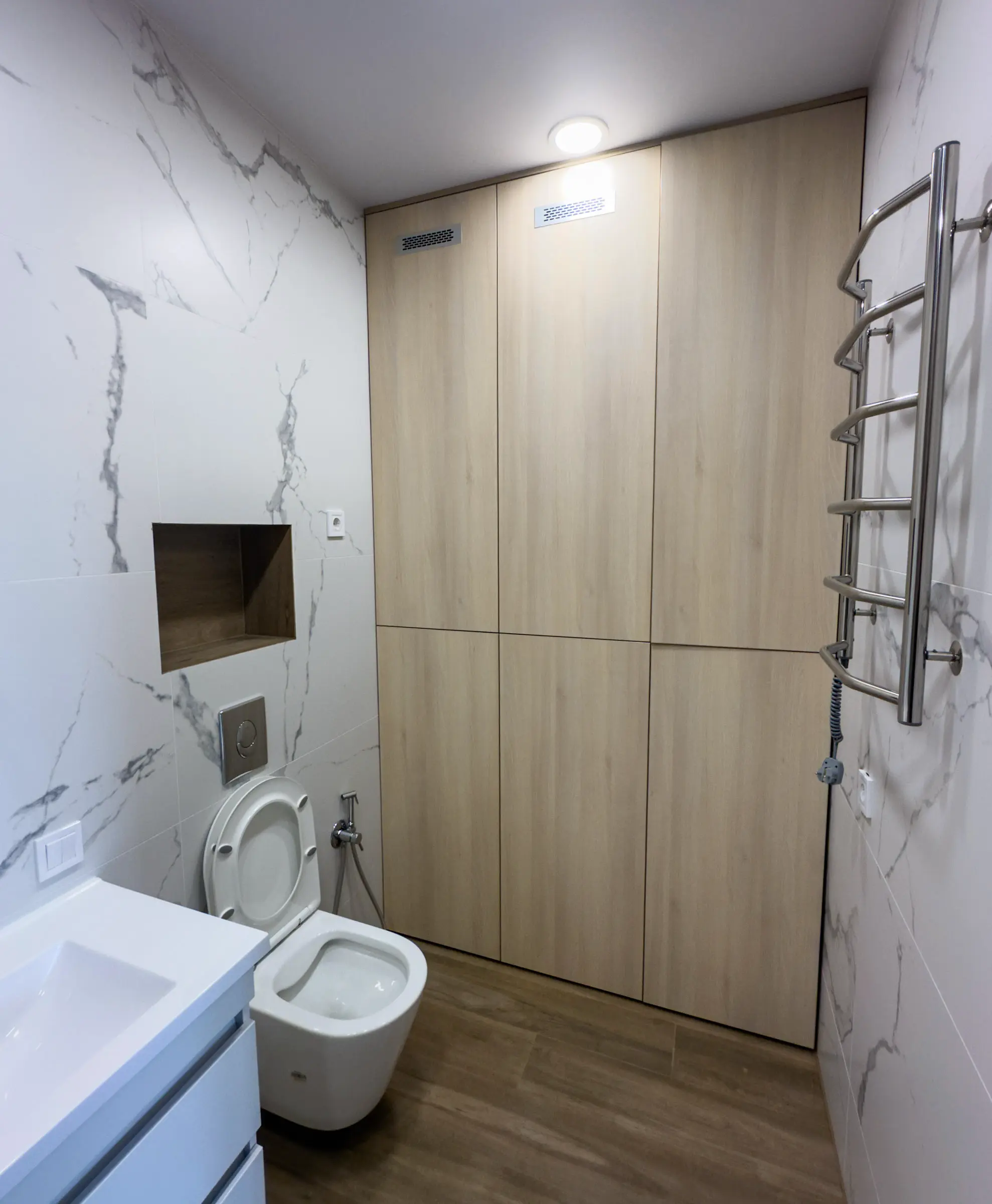 Bathroom: floor-to-ceiling wood-effect built-in wardrobe and a wall niche with marble-effect tiles